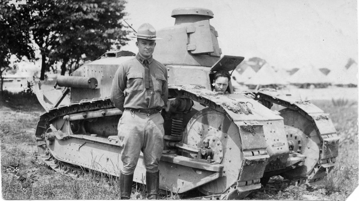 Dwight D. Eisenhower stands by a tank.