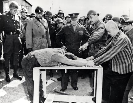 April 12, 1945 - Dwight D. Eisenhower watches as survivors of Ohrdruf demonstrate torture methods used at the camp